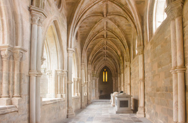 Fototapeta na wymiar The beautiful, sunlit cloister walkway of Cathedral of Evora in broad daylight. Gothic architecture in Portugal.