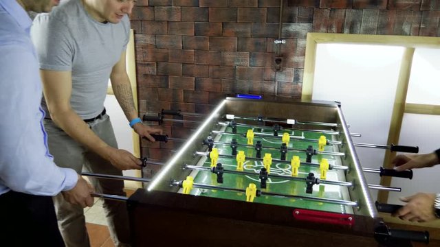 Sport, game concept. Foosball. Three men playing a table football or kicker with miniature players. 4K