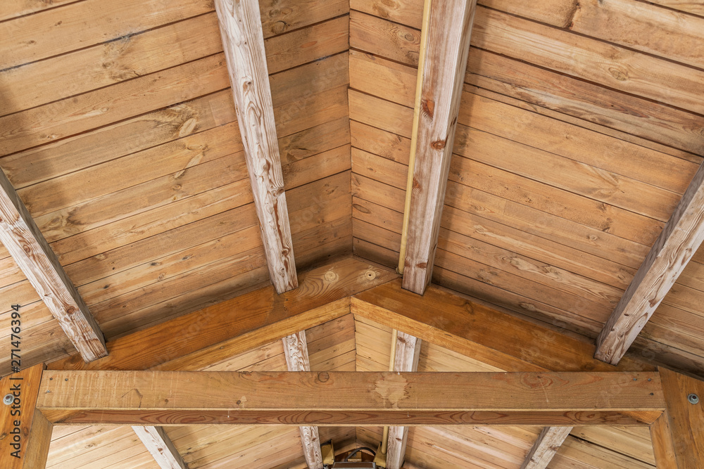 Wall mural background of wooden vaulted ceiling with bearing beams and rafters close up