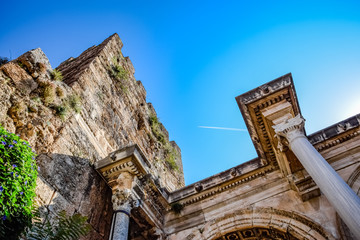 The plane leaving a condensation trail flies high above the gates of Hadrian.