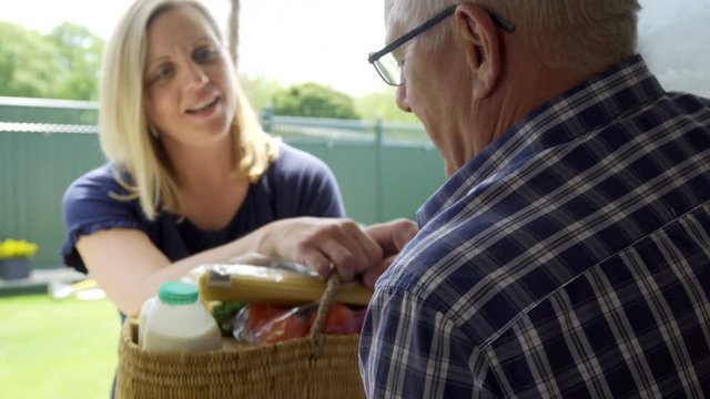 Mature Female Neighbor Helping Senior Man With Shopping