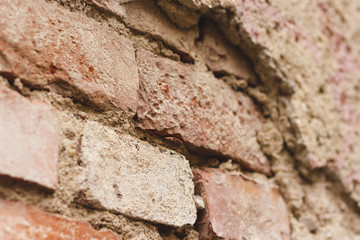 Perspective view of a weathered brick wall – Damaged and old building exterior with a rough surface and broken plaster