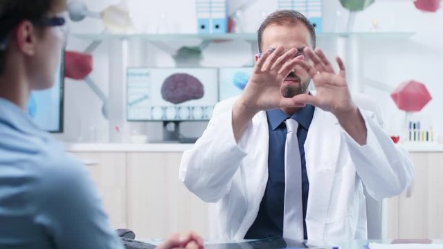 In modern research facility doctor is wearing augmented reality glasses and shows something to a patient