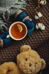 girl in mittens holding a cup of tea with lemon