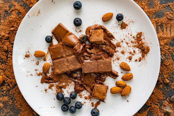 top view of the dessert with chocolate bar, blueberry, almond nuts on the white plates