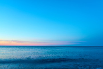 Obraz premium Waving sea water on a sunset against a blue sky. Copy space. 