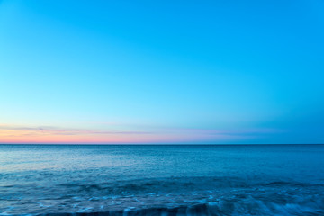                           Waving sea water on a sunset against a blue sky. Copy space.      