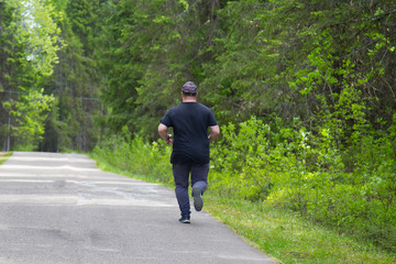 A fat man is running in the Park.