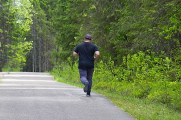 A fat man is running in the Park.