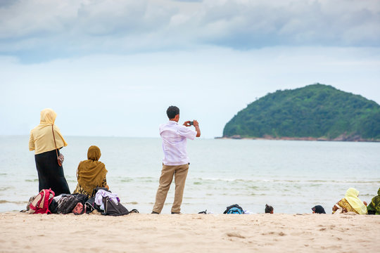 Rear view of a Muslims family relaxing on the sand beach on summer dusk.