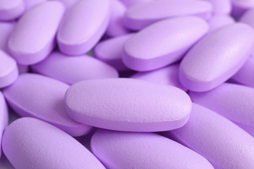 Obraz na płótnie Canvas Macro shot of heap of pastel purple oval shaped supplement pills
