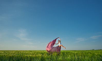 Classic dance on nature background. Professional female modern dancer in pink fabric dress dancing...