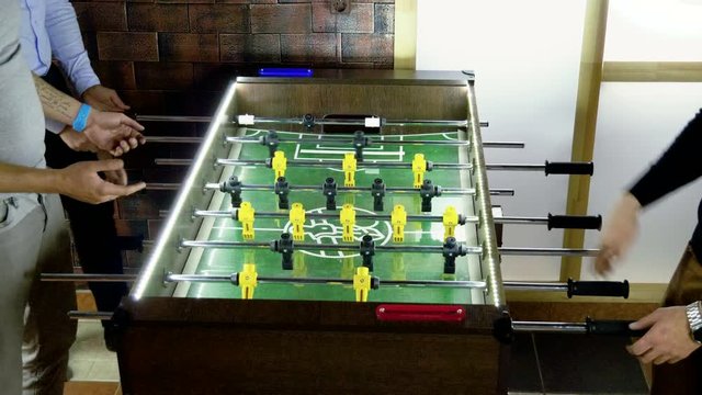 Sport, game concept. Foosball. Three men playing a table football or kicker with miniature players. 4K
