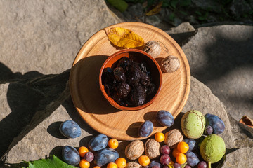 Fresh and dried prunes on plate.
