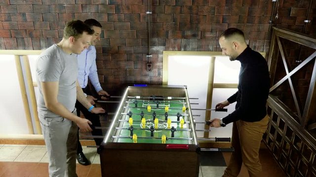 Sport, game concept. Foosball. Three men playing a table football or kicker with miniature players. 4K