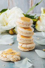 macarons and white peony flowers on wooden surface   