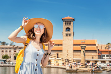Asian girl traveler with big hat and backpack on vacation in the popular Greek island of Rhodes