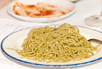 Top, front view, close distance of a white, round dish of spaghetti with garlic and olive oil gravy , served as a pairing for red, italian wine at a tropical wine tasting event