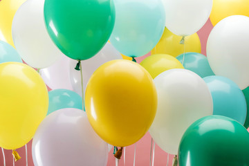 close up view of multicolored decorative balloons on pink background