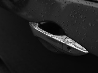 Obraz na płótnie Canvas Close up of water droplets on grey car door handle.