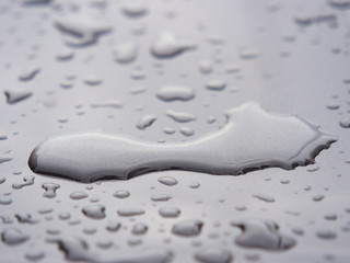 Close up of water droplets on grey car.
