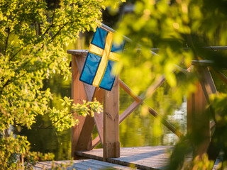 Swedish flag on a floating dock in summer sunset light in Sweden.