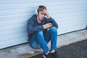 Teenager listening to music and viewing something upsetting on his cellphone.