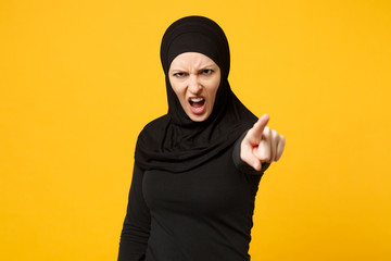 Sad upset crying confused young arabian muslim woman in hijab black clothes posing isolated on yellow wall background, studio portrait. People religious Islam lifestyle concept. Mock up copy space.