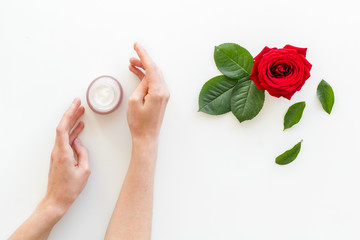 Natural floral cosmetics with rose flowers for face and body care in hands on white background top view