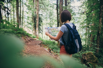 Woman looking at the map while hiking in forest.