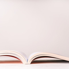 Close view of an open book in a pink design on a pink pastel background with copy space. Mock up of reading book concept.