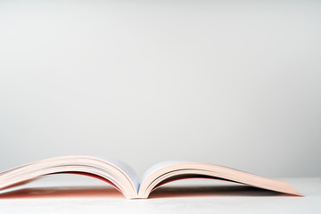 Close view of an open book in a pink design on  light  background with copy space. Mock up of reading book concept.