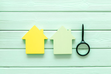 Search for a new house concept with house figure and magnifier on mint green wooden office desk...