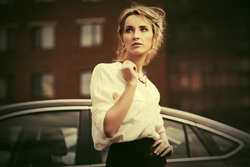 Young fashion business woman in white shirt next to her car