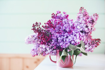 It's spring. Fresh fragrant bouquet of lilac in a vase with a heart on a mint wooden background. Romance