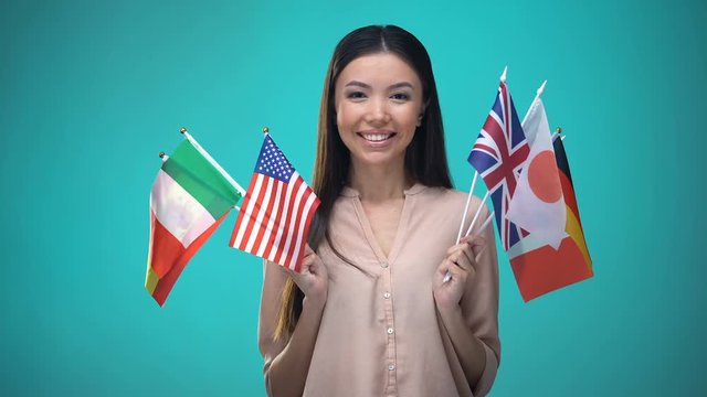 Woman holding many flags, choosing country to travel, international relations