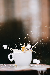 cup of coffee with milk splash on black background