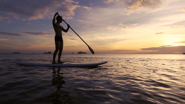 Silhouette Of Man On SUP Paddle Standing Board At Sunset, Beach Leisure Activity Video