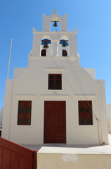Santorini. Dzwony na wieży kościoła na tle błękitnego nieba.