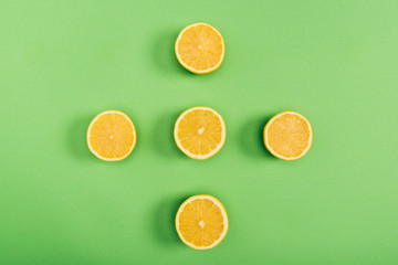 Top view of yellow and delicious cut lemons on colorful green background