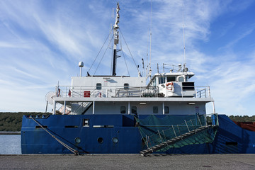 Stern of cargo vessel at port. Gangway arrangment. Blue hull. White superstructure. © Alexander
