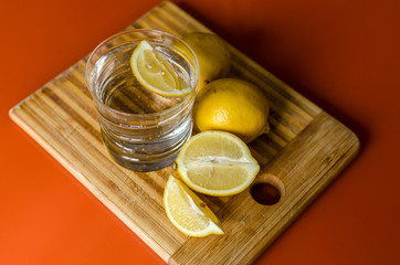 Citrus lemonade, a glass of water with slices of lemon to quench your thirst on the Board on the table with a blurred background. The concept of detoxification, proper nutrition and healthy lifestyle