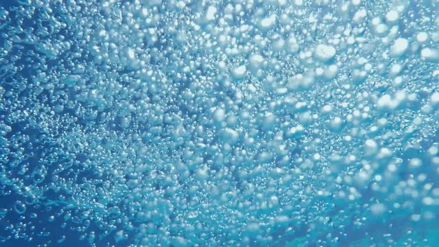 Bubbles rising to the surface. Slow motion. Air bubbles in clear blue water (underwater shot), good for backgrounds