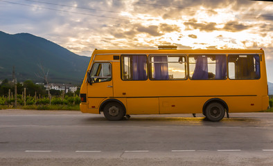 bus goes along the road along the mountains at sunset