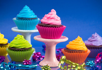Rainbow Colored Frosted Chocolate Cupcakes with Confetti and Bows for a Party