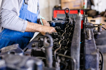 Obraz premium Mechanic opened the locking valve mechanism. Disassemble engine block vehicle. Old motor capital repair. Car service concept