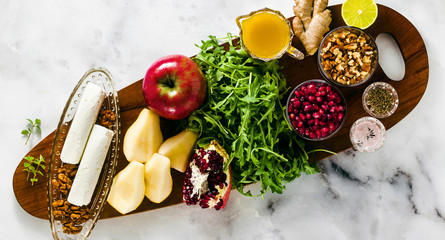 banner of ingredients for cooking Pomegranate & Pear Green Salad with Ginger Dressing on a wooden board on white marble