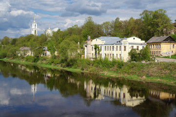 Provincial russian town of Torzhok at spring sunny day. Panoramic view of the Tvertsa river embankment with old houses and church