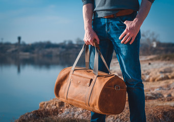 Man with leather travelbag on tha lake shore 