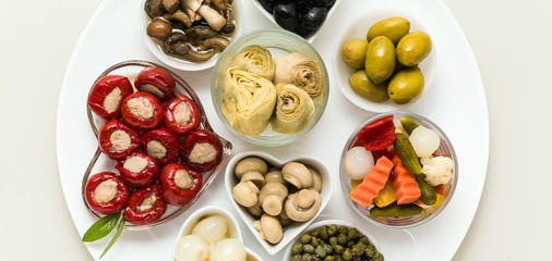 banner of Italian traditional pickles on a plate. tuna stuffed peppers, artichokes in oil, olives, mushrooms, capers. copy space.